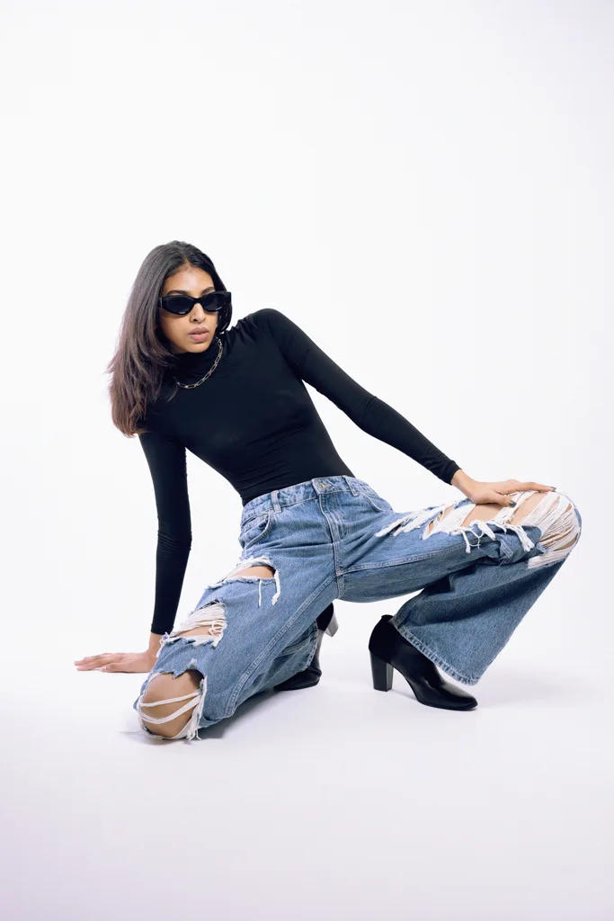 Streetwear fashion shot, model in sunglasses crouched in wide denim, photographed by Shreyak Singh