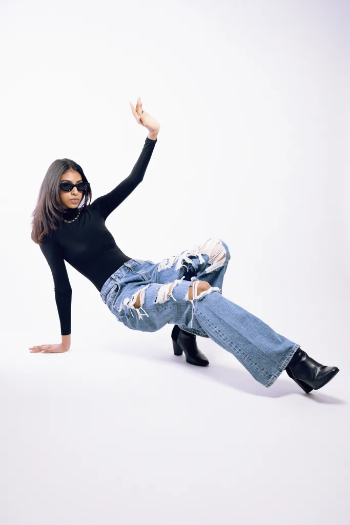 Studio fashion photograph, model in a black turtleneck and blue jeans mid-pose, photographed by Shreyak Singh