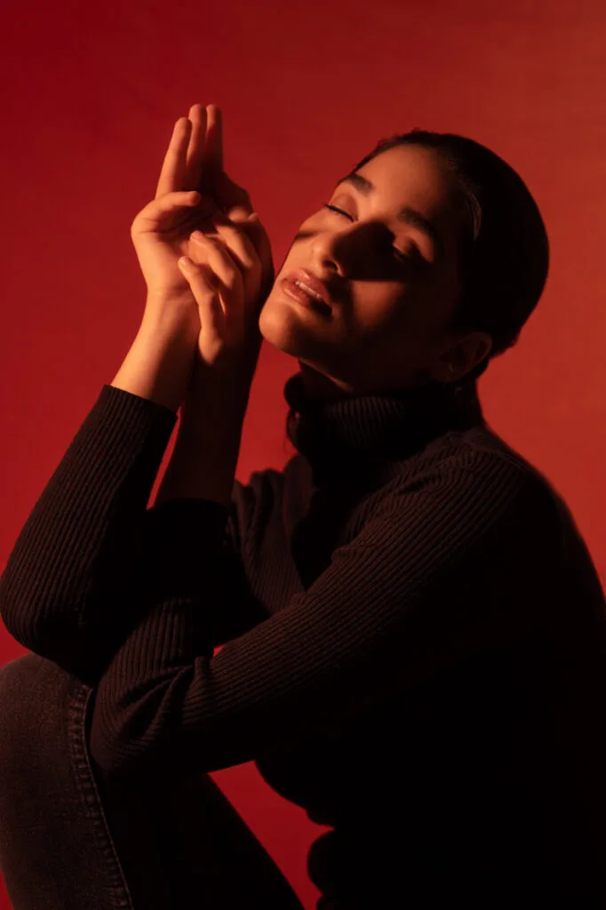Fashion photograph in red light, model with hands raised, photographed by Shreyak Singh